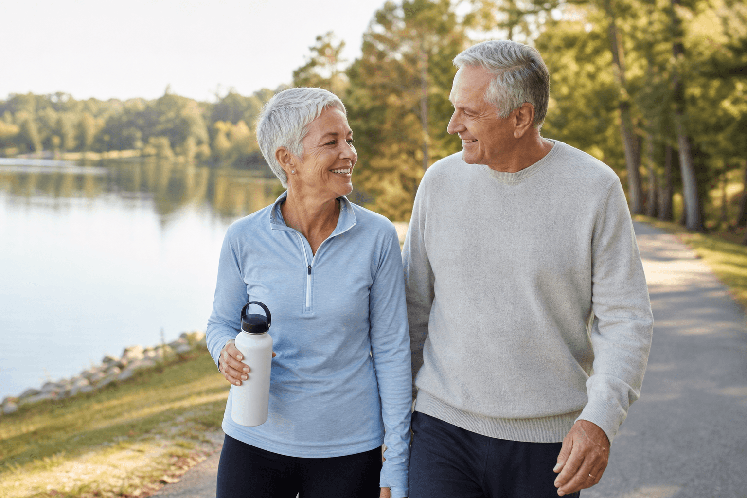 Senior couple enjoying an active walk along a lakeside path after recovery